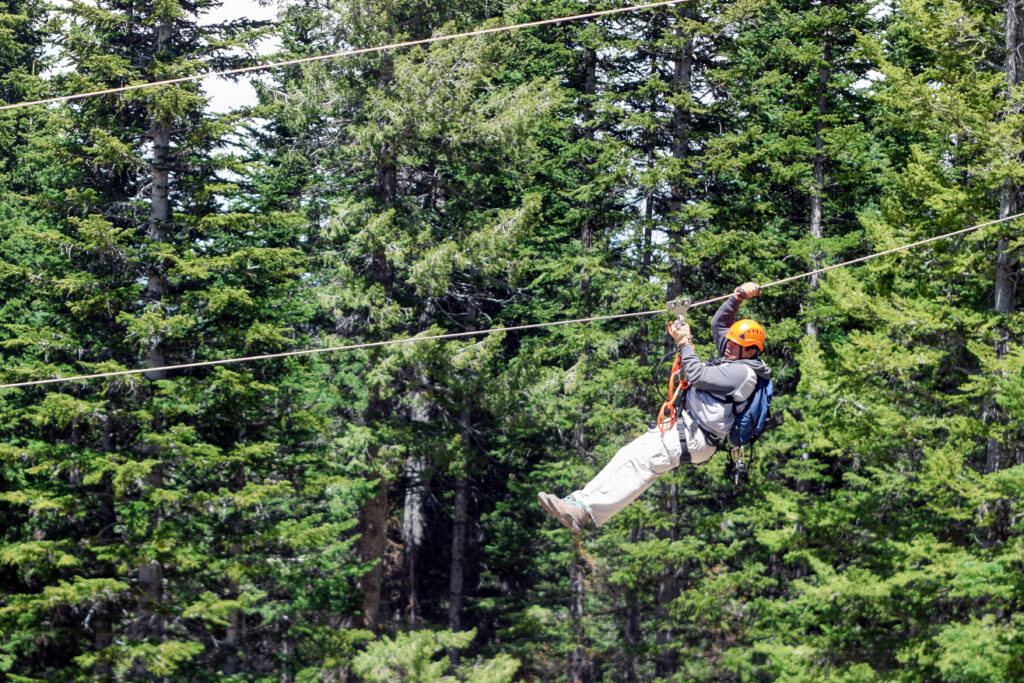 Photo of a person zip-lining through the woods of Sunrise Park Resort, owned by the White Mountain Apache Tribe Greer, Arizona