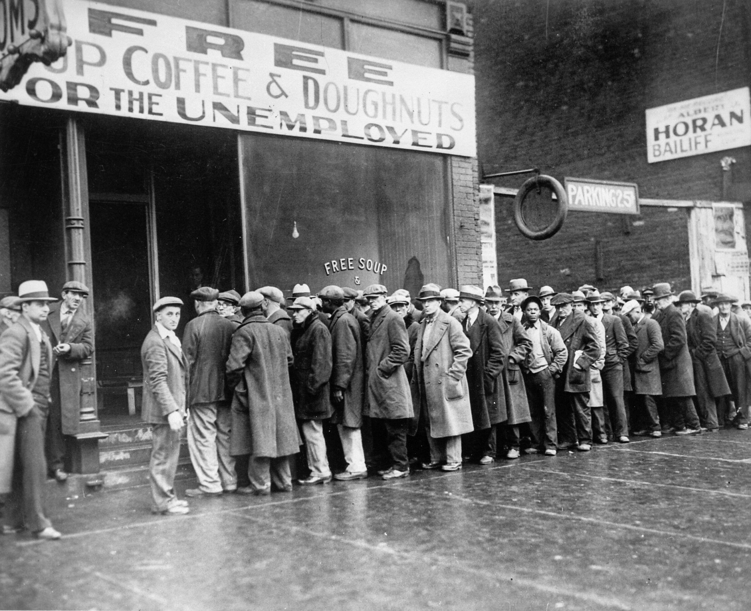Black and white photo of men standing in line waiting for food during the Great Depression.